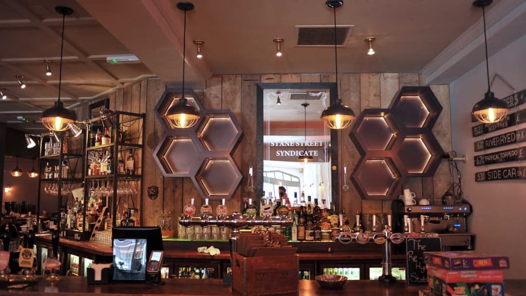 Completed bar fit-out with timber back bar, fitted shelving and warm pendant lighting